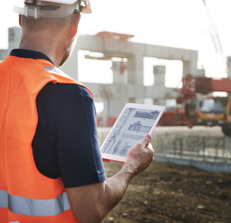 A man with a tablet at a construction site utilizing Microsoft Office 365 software solutions for document management thanks to HingePoint's implementing tailored Document Management Solutions for his company.