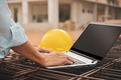 Close-up construction worker using procore sharepoint bi on building site